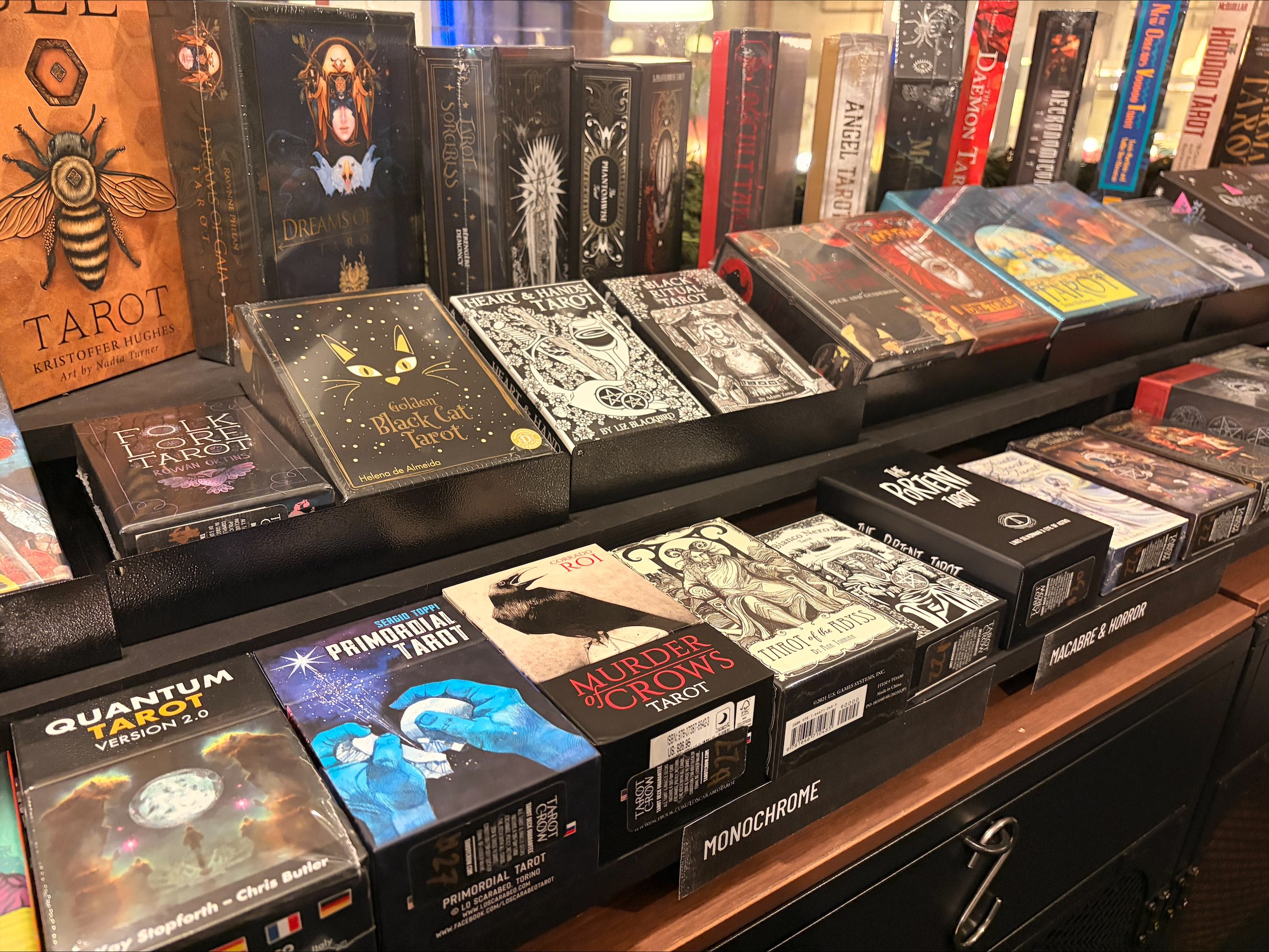 Photo shows variety of Tarot card decks arranged on a shelf